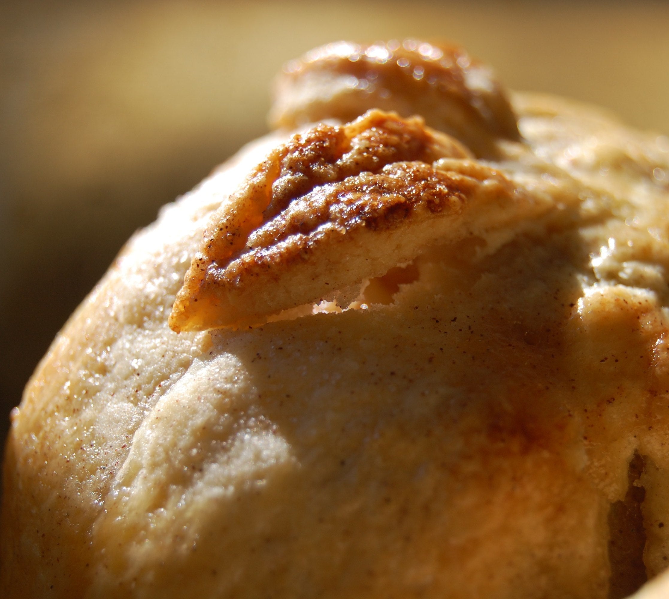 Close-up of baked apple en croûte showcasing golden flaky crust and decorative pastry leaf with warm blurred background