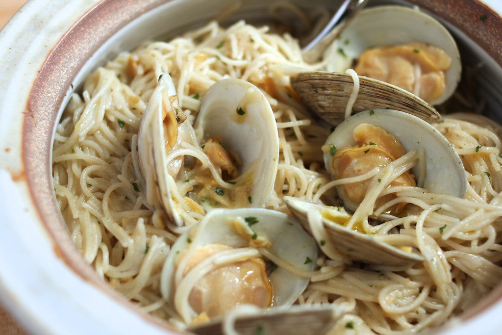 Bowl of capellini tossed with littleneck clams in a light garlic and olive oil sauce with parsley