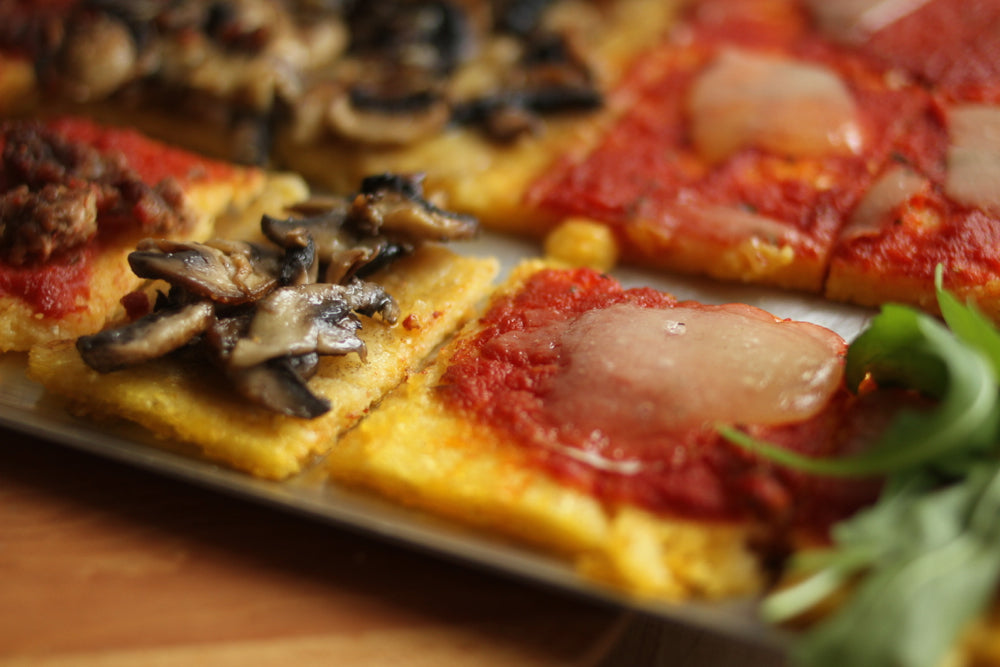 Slices of pizza with mushrooms, tomato sauce, melted cheese and arugula on a baking sheet
