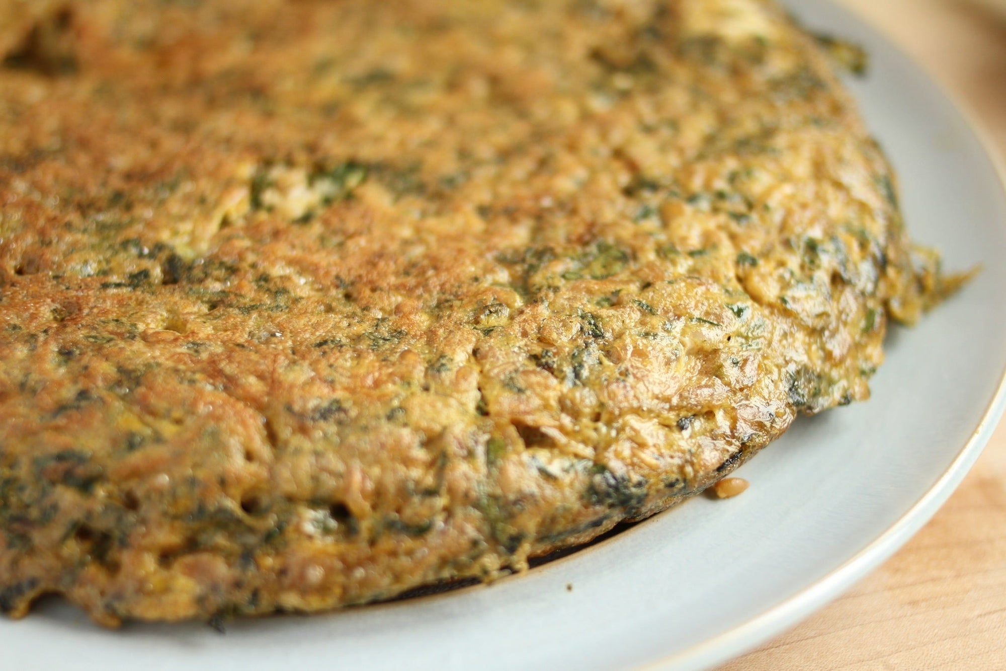 Golden-brown herb and spinach frittata on a white plate
