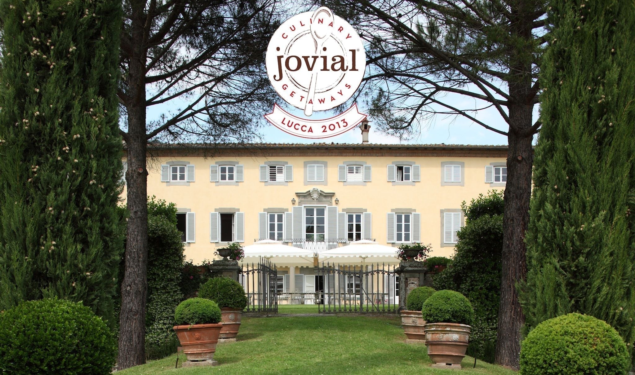 Jovial logo CULINARY GETAWAYS jovial LUCCA 2013 over a yellow Tuscan villa framed by cypress trees and potted boxwoods