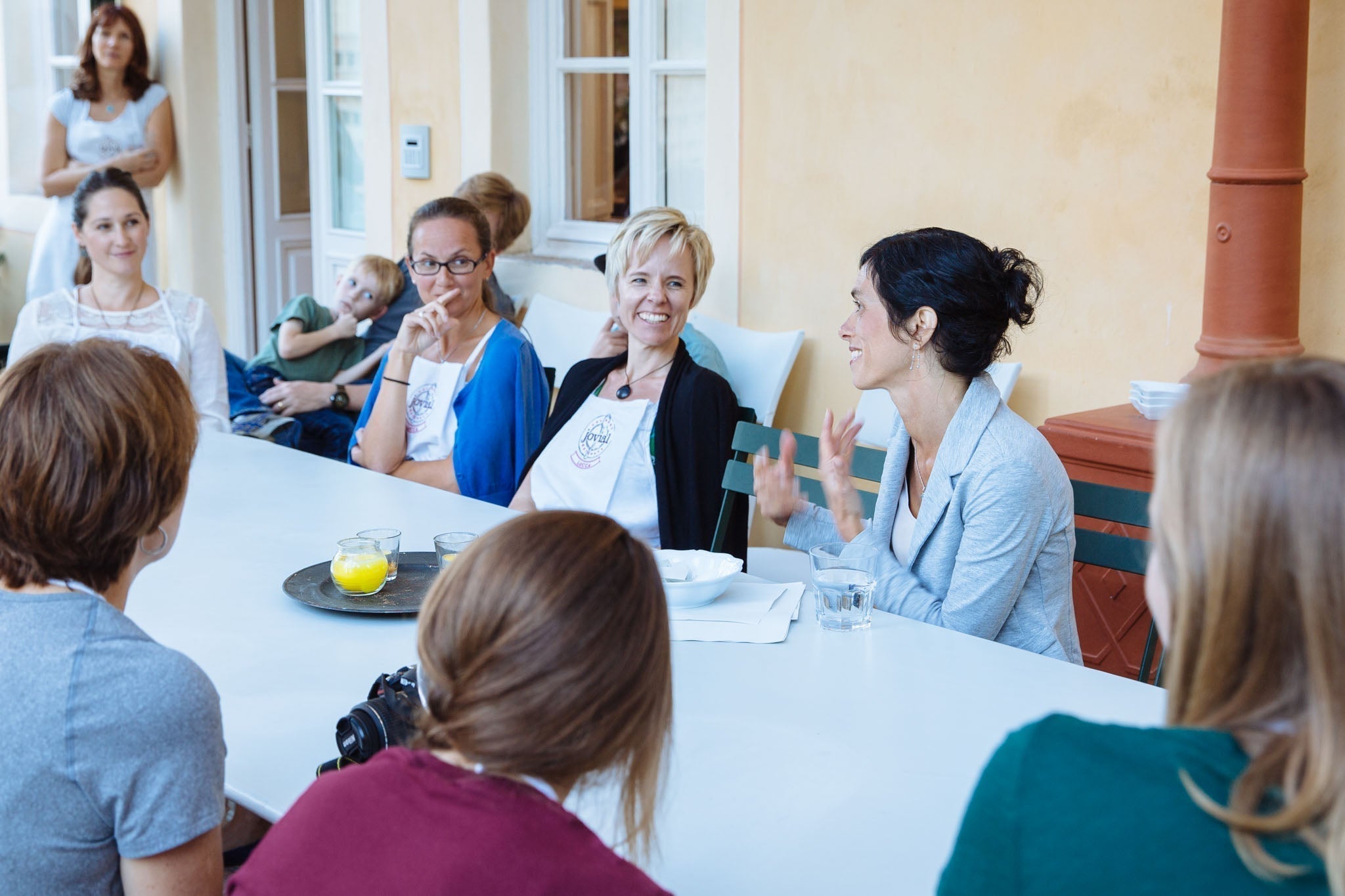 Women at a Jovial Foods workshop seated around a table; one woman speaking while others listen.