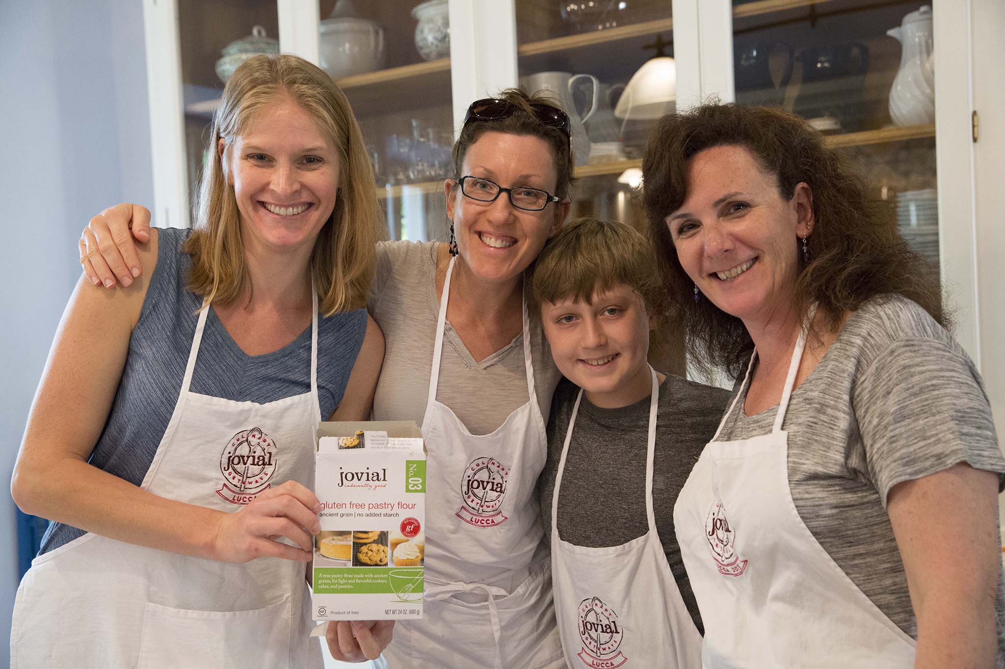 Four people hold a box labeled 'jovial gluten free pastry flour No.03 ancient grain no added starch Product of Italy Lucca'