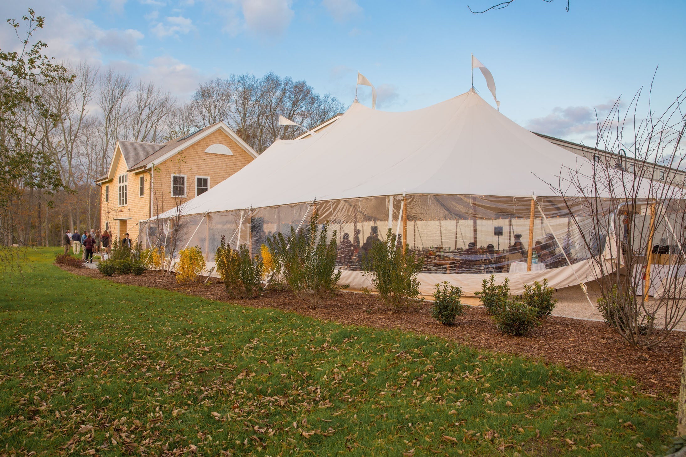 Jovial Foods grand opening: white sail style event tent beside the 1685 John Randall Homestead with guests seated inside and mingling outside