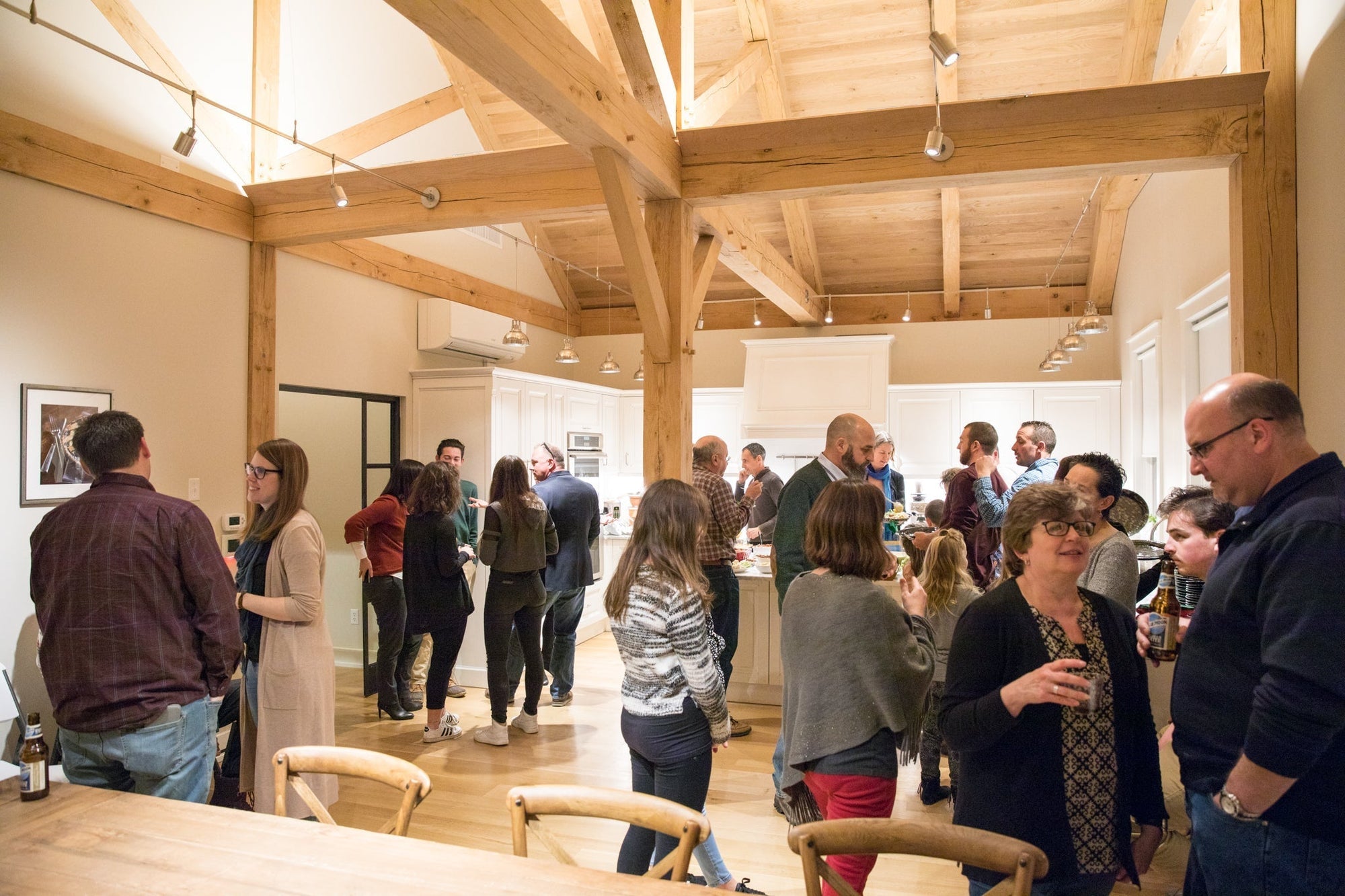 People socializing in a warm, timber-beamed kitchen during a casual gathering