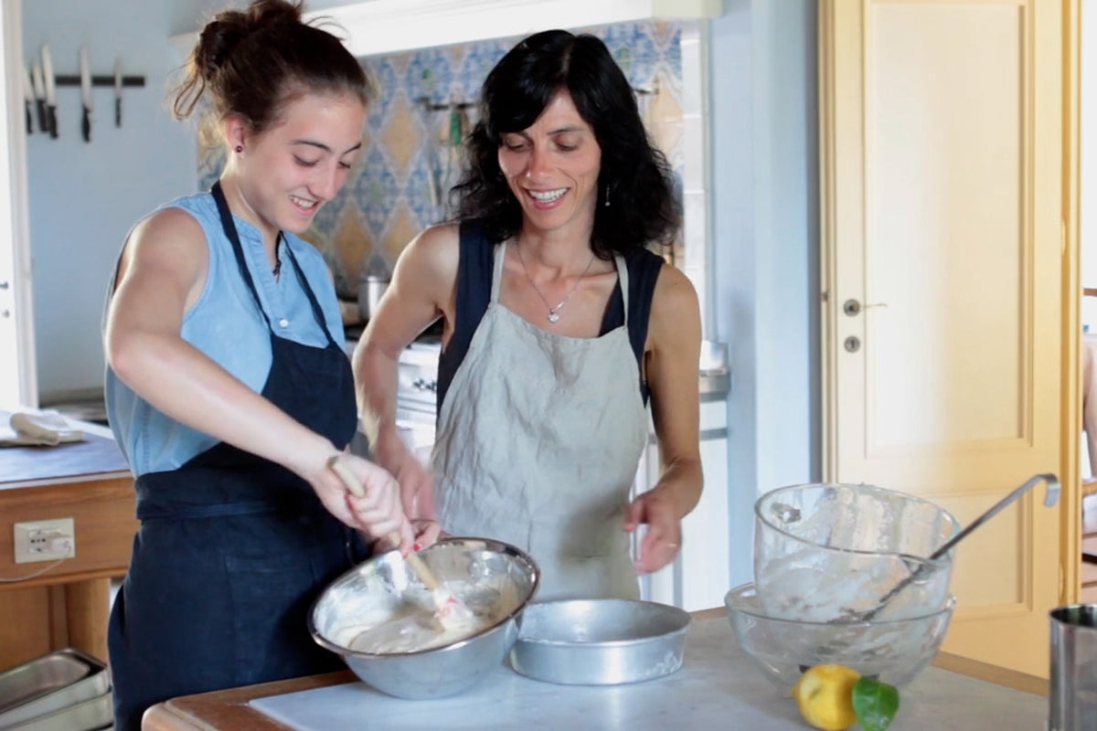 Giulia and Carla stirring batter in a home kitchen, mixing bowls and a lemon on the counter