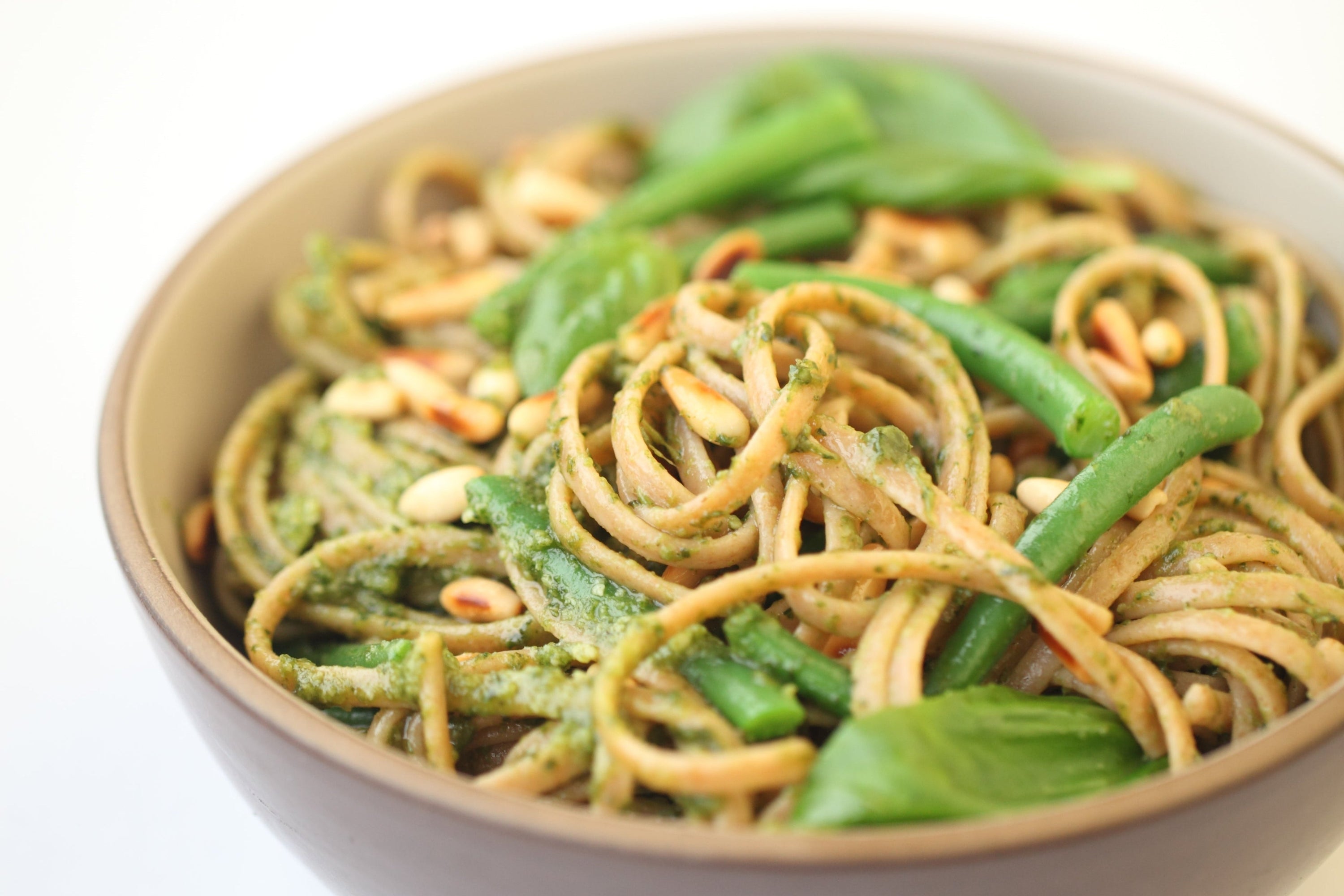 Bowl of linguine tossed in pesto with green beans and toasted pine nuts
