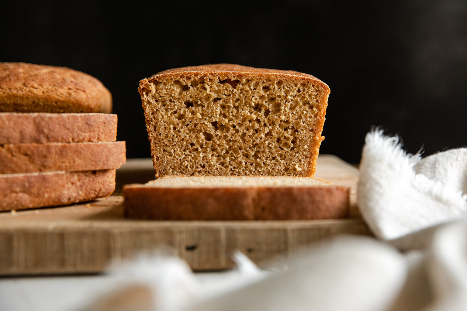Front-facing cross-section of whole grain Einkorn loaf showing open crumb and golden brown crust on a wooden cutting board
