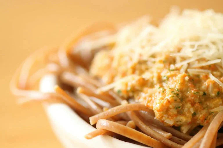 Close-up of a plate of whole-grain einkorn linguine topped with roasted pepper and almond pesto and grated cheese