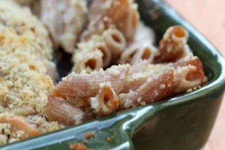 Baked einkorn macaroni and cheese in a green ceramic baking dish with golden breadcrumb topping