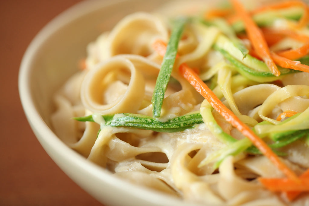 Bowl of tagliatelle in creamy primavera sauce with julienned zucchini and carrot