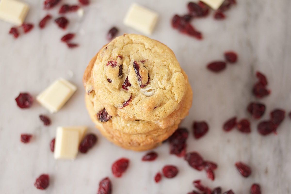 Top-down view of Einkorn cookies with white chocolate chunks and dried sour cherries on marble surface