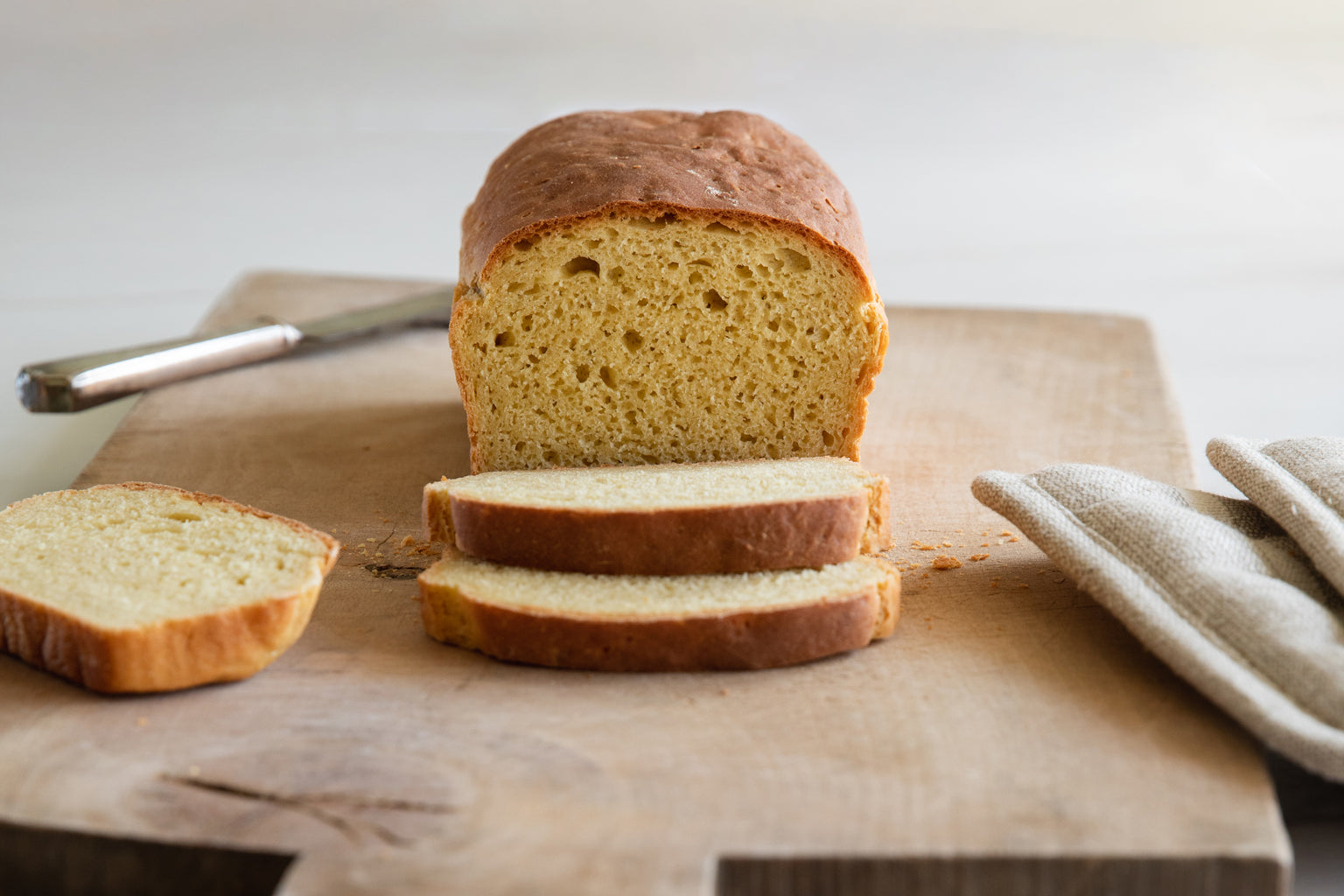 Front view of sliced Einkorn sandwich loaf showcasing its soft golden crumb and brown crust on a wooden cutting board with a linen napkin