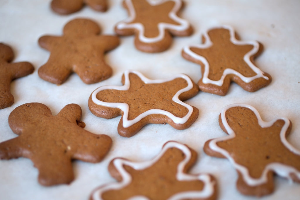 Top-down view of gingerbread cookies made with einkorn flour, some decorated with white icing outlines on parchment