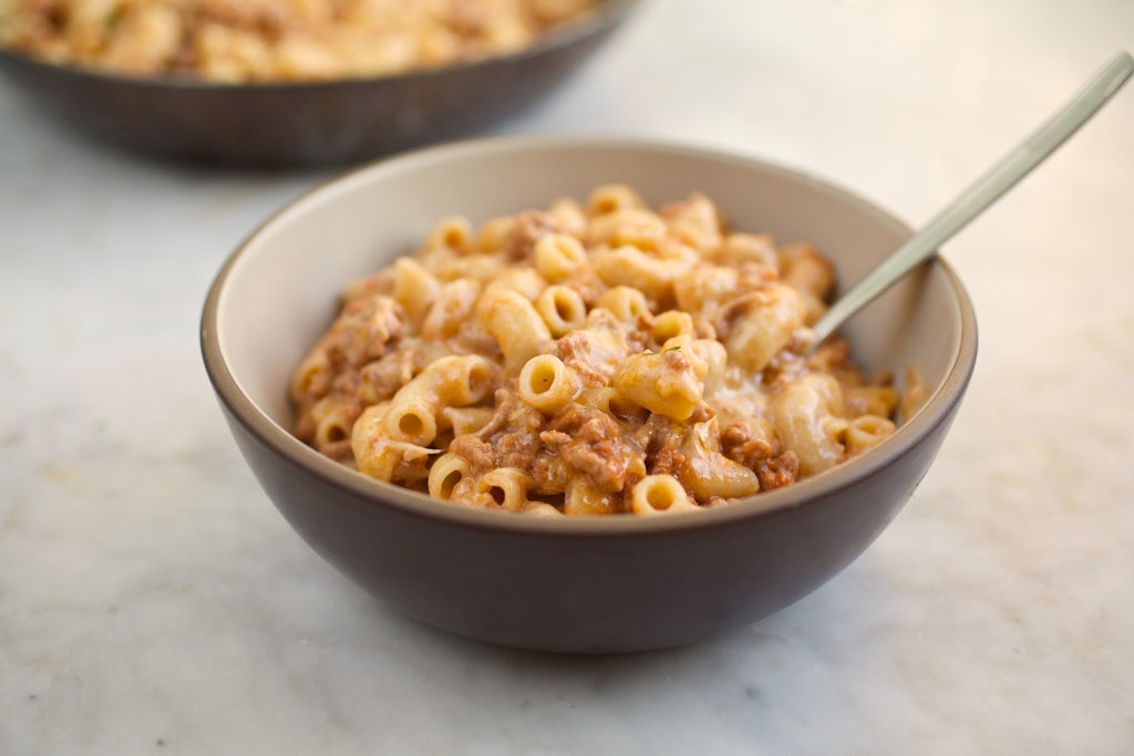 Brown bowl of gluten free hamburger helper with elbow macaroni and ground beef on marble countertop