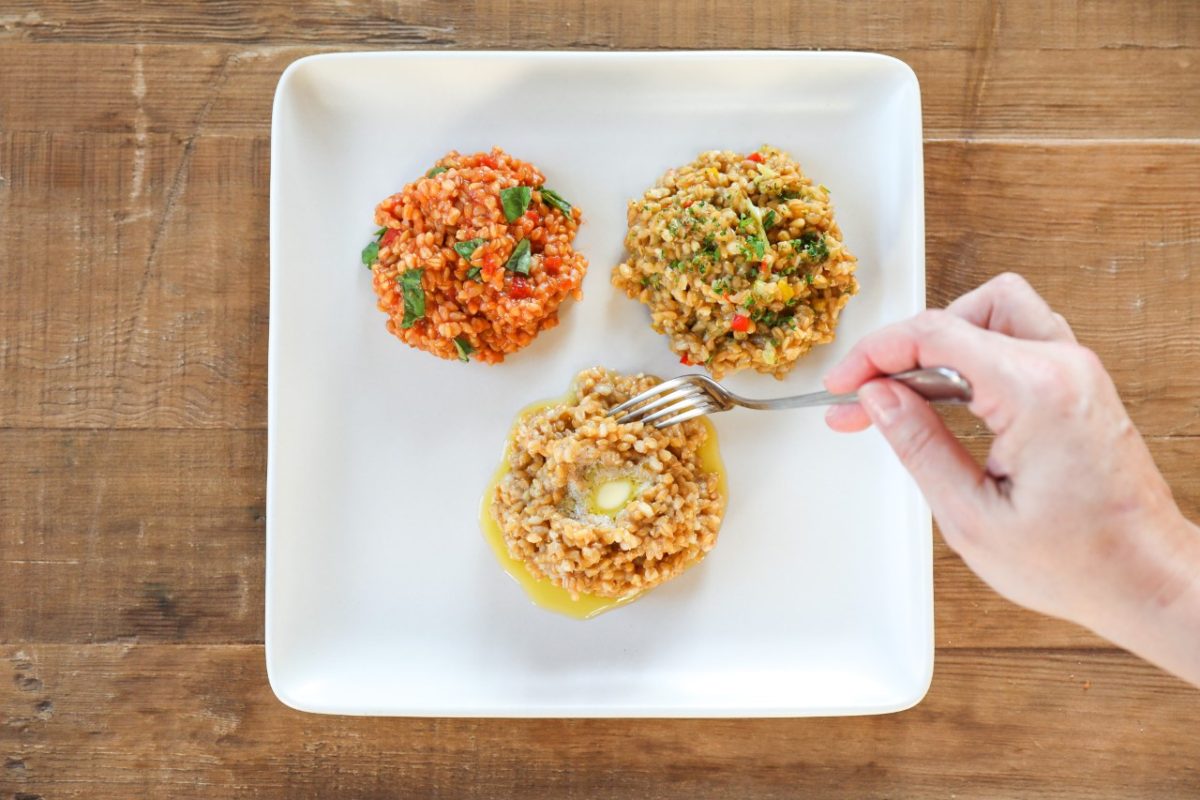 Three wheat berry grain bowls on a white square plate, one being pierced with a fork on a wooden table