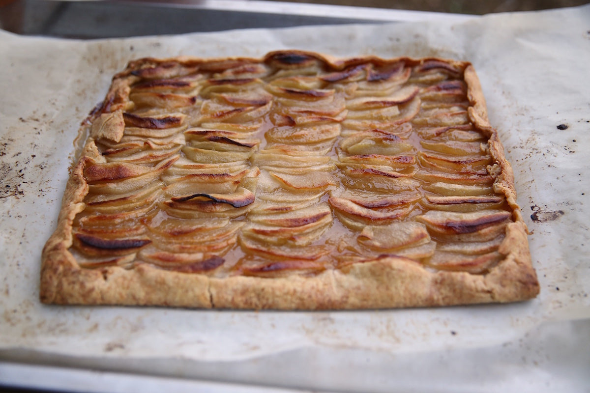 Close-up of Einkorn apple caramel tart showing overlapping baked apple slices and caramel glaze on parchment