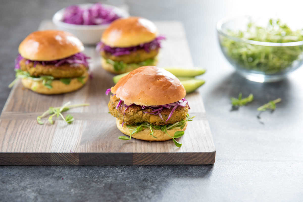 Chickpea burger sliders on brioche buns with shredded red cabbage and microgreens on a wooden board