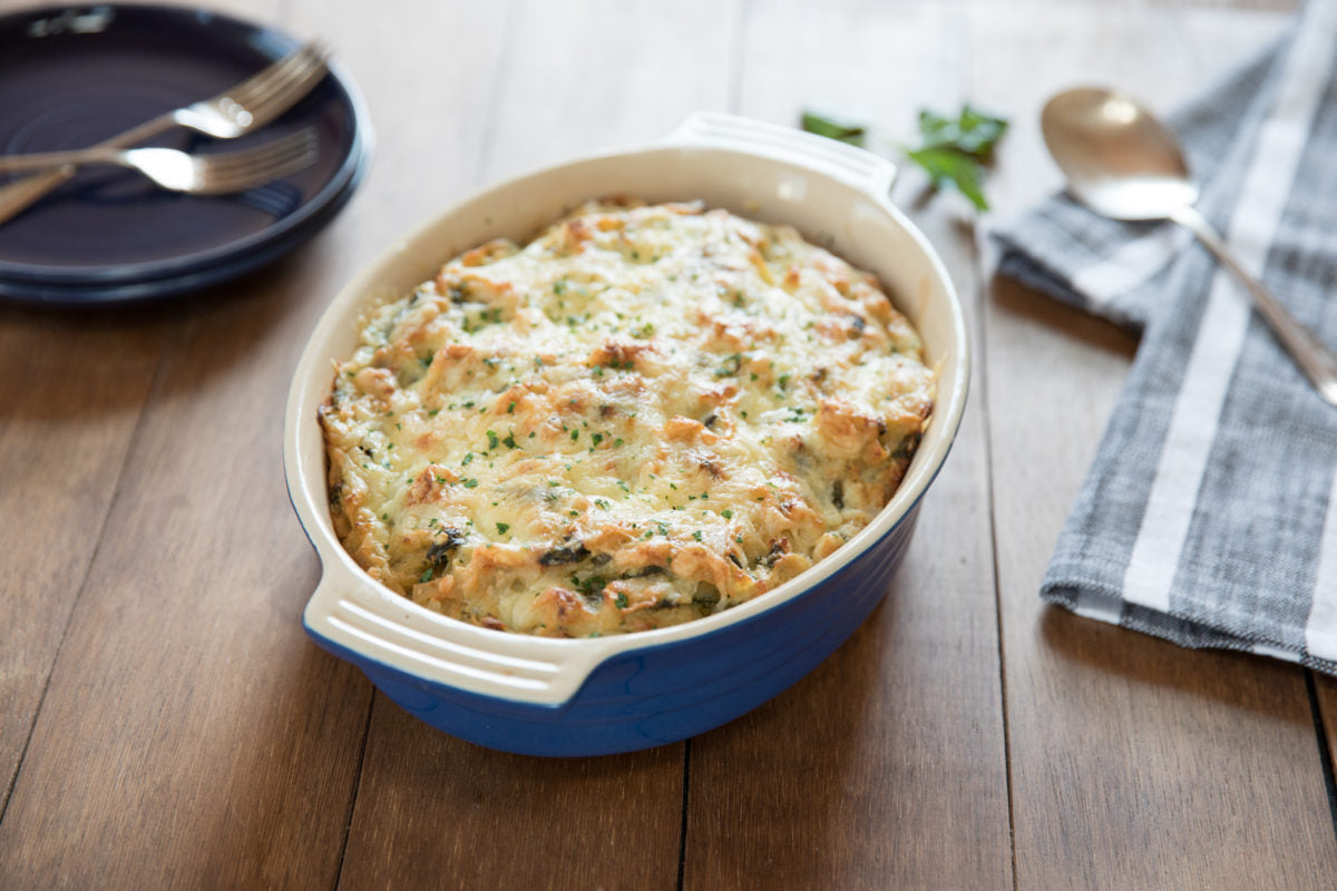 Three-quarter view of gluten-free tuna noodle casserole in blue baking dish with golden cheese topping on wooden table