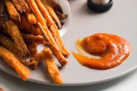 Close-up of Jovial tomato ketchup on a white plate showing smooth texture and rich red color beside crispy fries