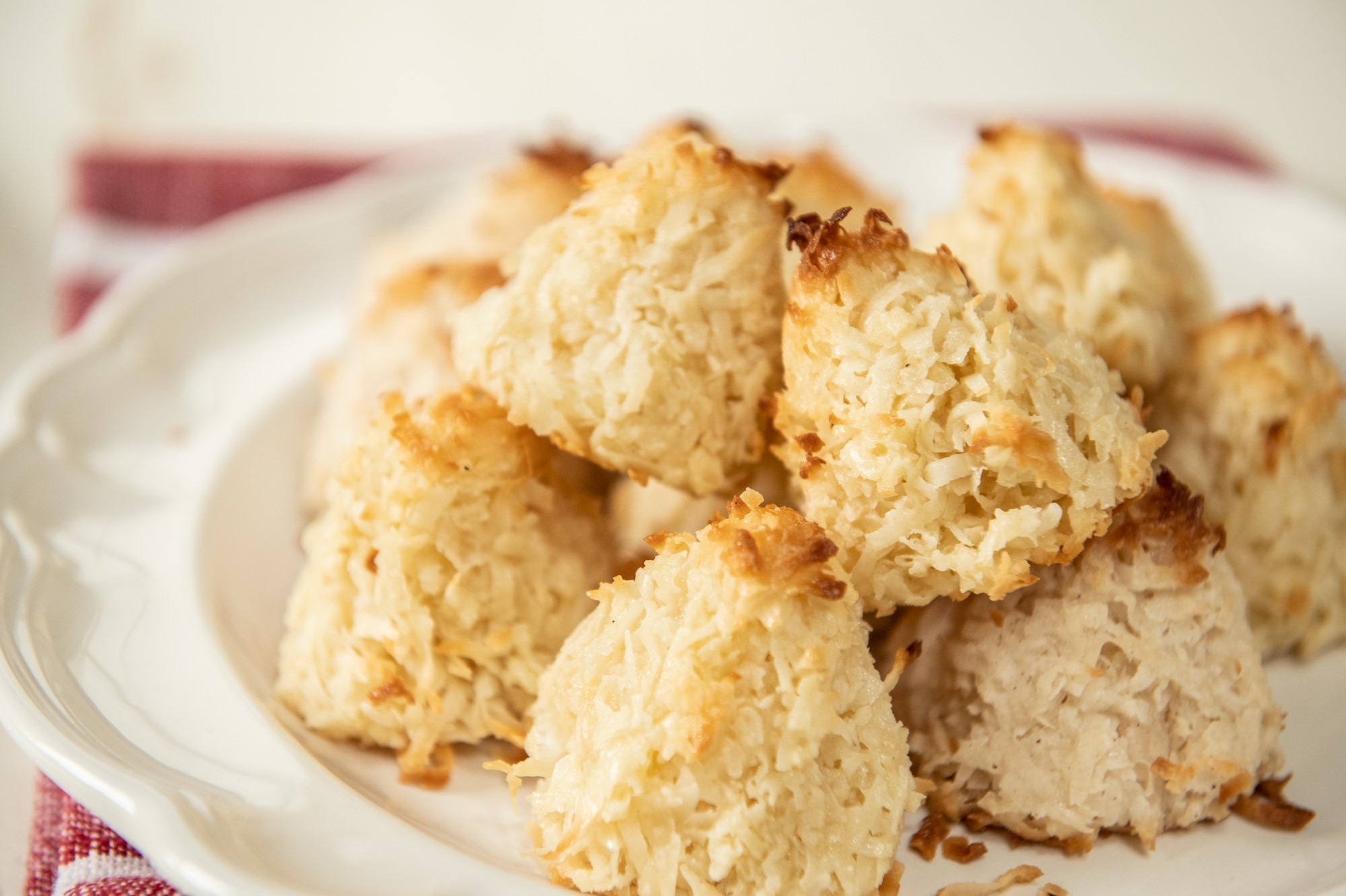 Close-up of coconut macaroons showing golden-browned shredded coconut texture on a white plate with a red napkin