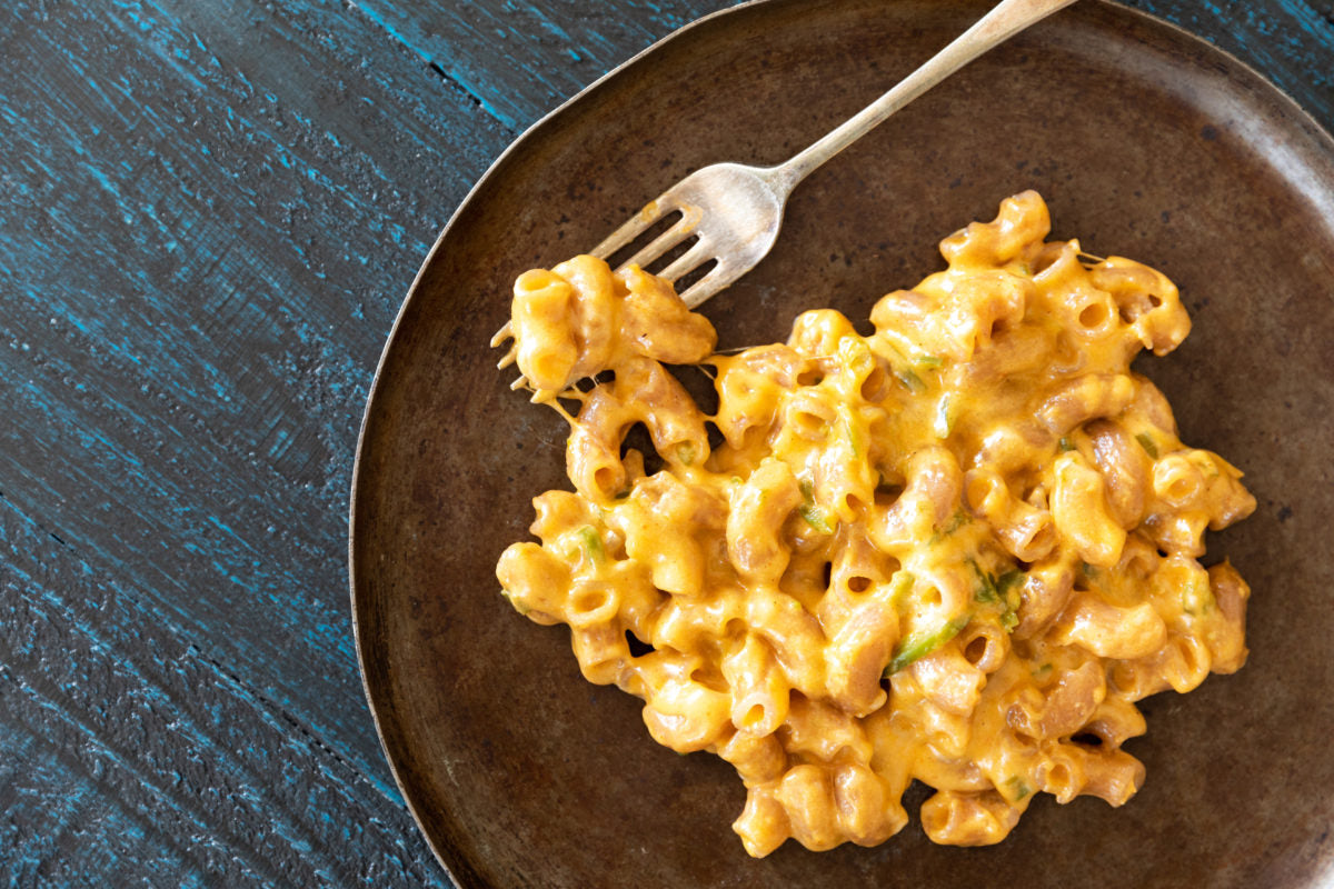 Mexican-style one-pot mac and cheese with cassava elbow pasta on a dark plate with a fork