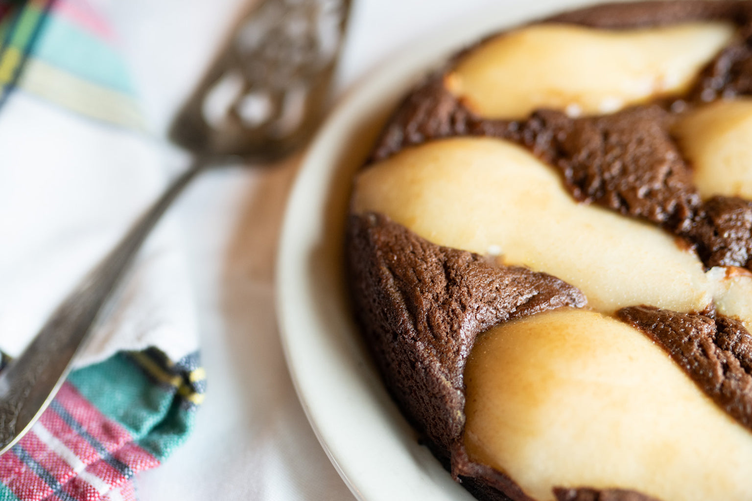 Close up of chocolate pear pudding cake in a round ceramic dish with pear halves baked into chocolate batter on a cloth