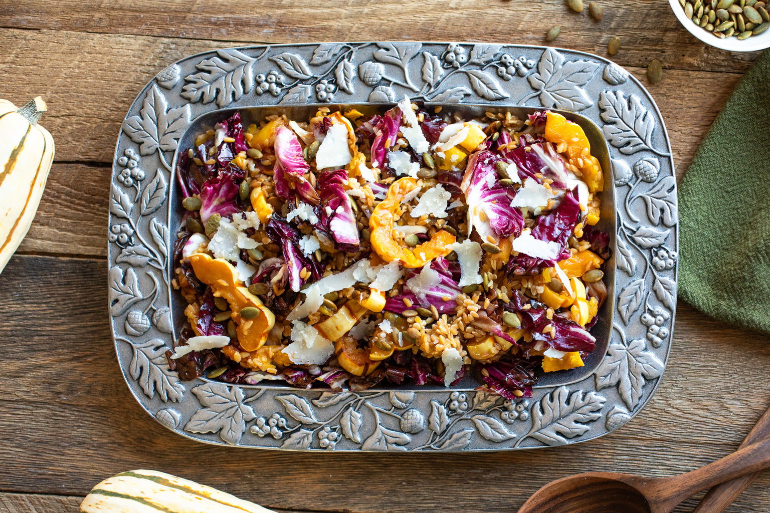 Wheat berry salad with roasted delicata squash and radicchio in a decorative metal serving dish on a wooden table