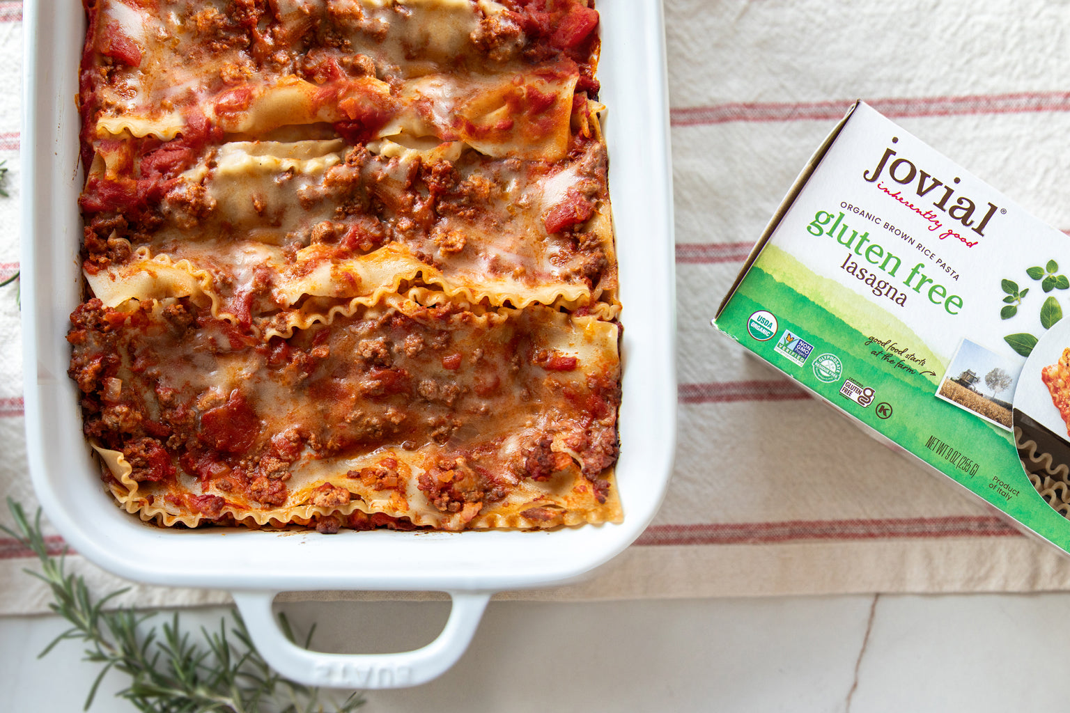 Dairy-free gluten-free lasagna Bolognese in a white baking dish beside a Jovial gluten-free lasagna box