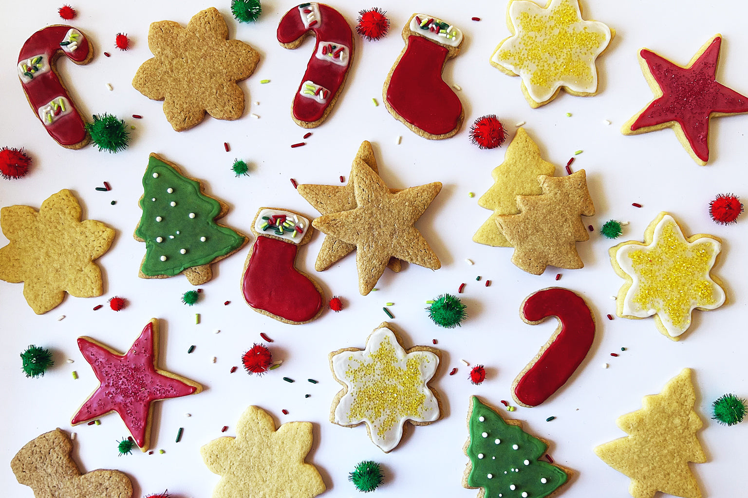 Overhead view of Einkorn sourdough sugar cookies in holiday shapes decorated with red and green icing on white background