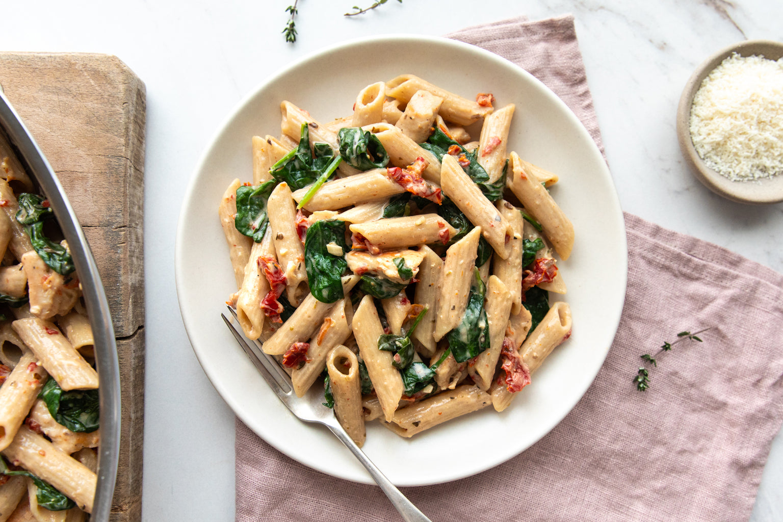 Top-down view of Marry Me Chicken Pasta showing penne in creamy sauce with spinach and sun-dried tomatoes on a white plate with a fork