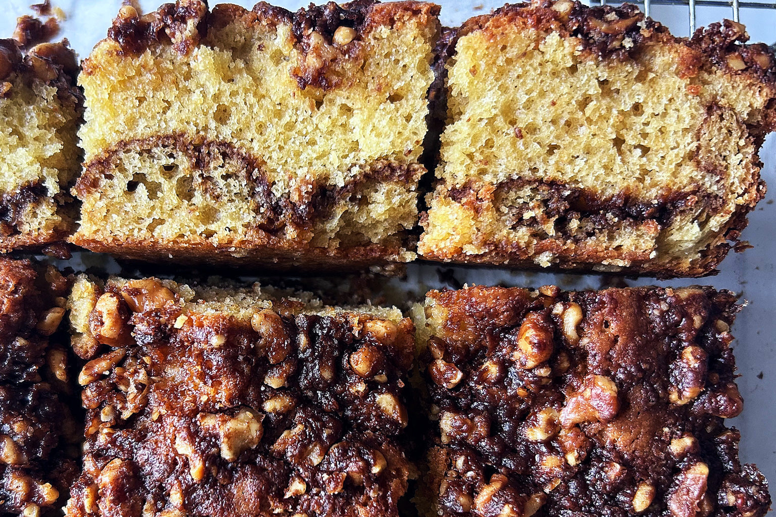 Overhead view of sourdough cinnamon coffee cake slices with walnut crumble topping and cinnamon swirl on a cooling rack