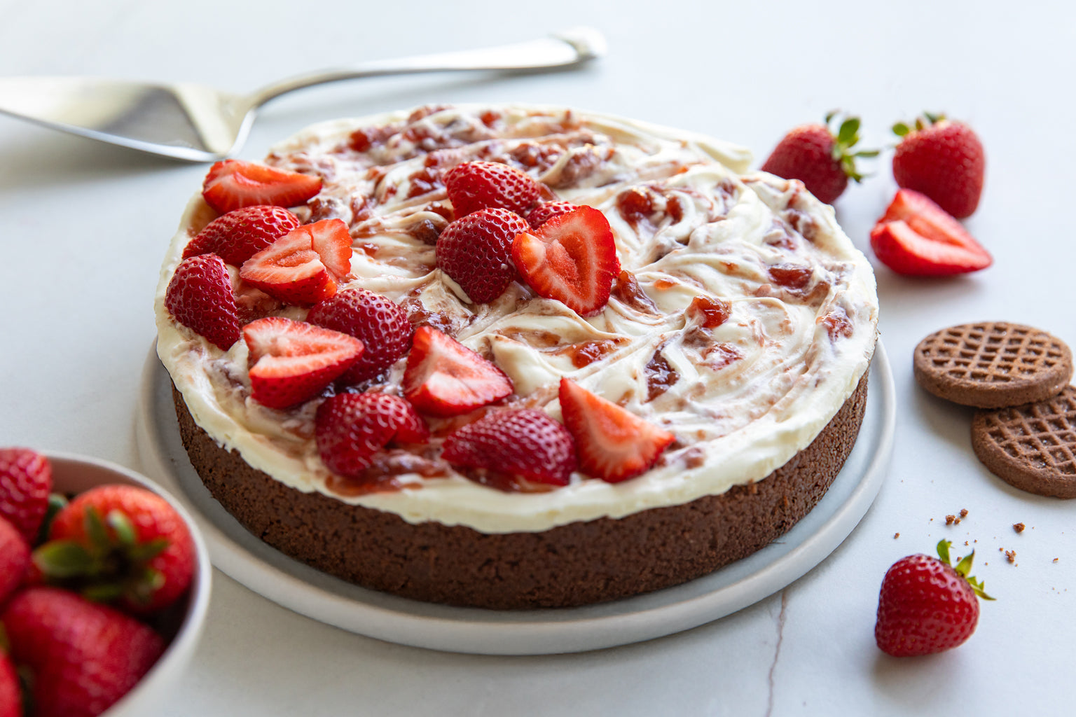 Angled view of no-bake crispy cocoa cheesecake showcasing cocoa cookie crust and swirled cream topping with strawberries