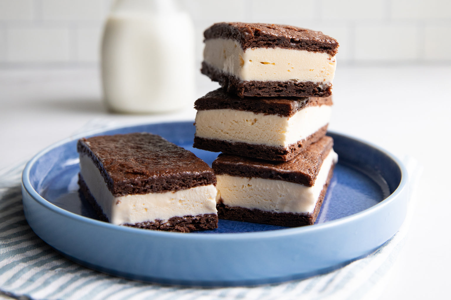 Close-up of stacked Einkorn ice cream sandwiches with thick vanilla filling between chocolate cookie layers on a blue plate