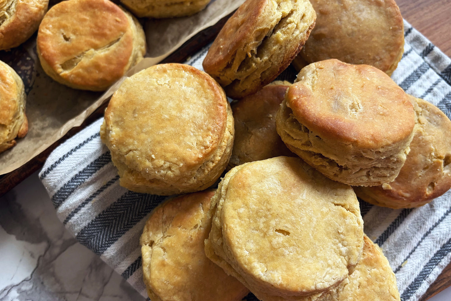 Overhead view of Einkorn sourdough biscuits showing flaky layers and golden-brown tops on a striped kitchen towel