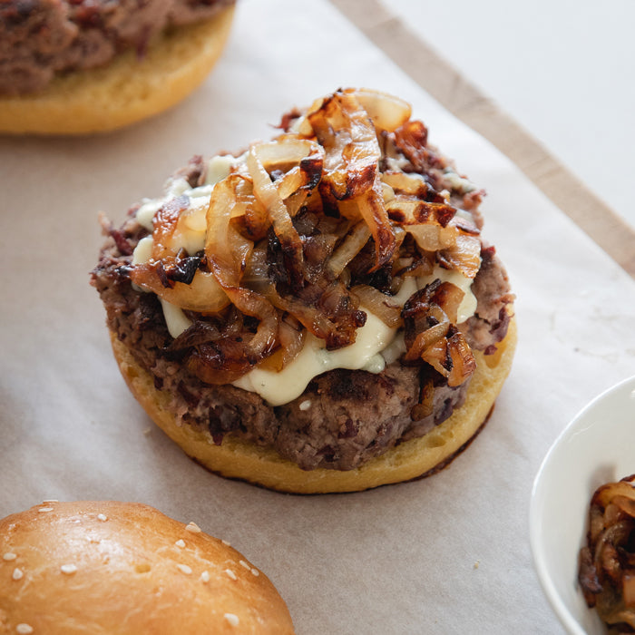 Close-up of kidney bean burger on a bun showcasing melted cheese and caramelized onions on a parchment-lined board