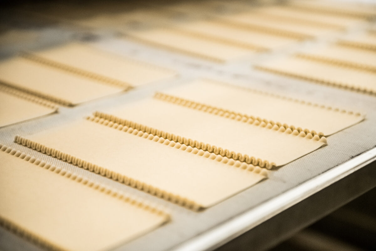 Fresh pasta sheets with fluted edges on a drying tray at an artisan pasta maker