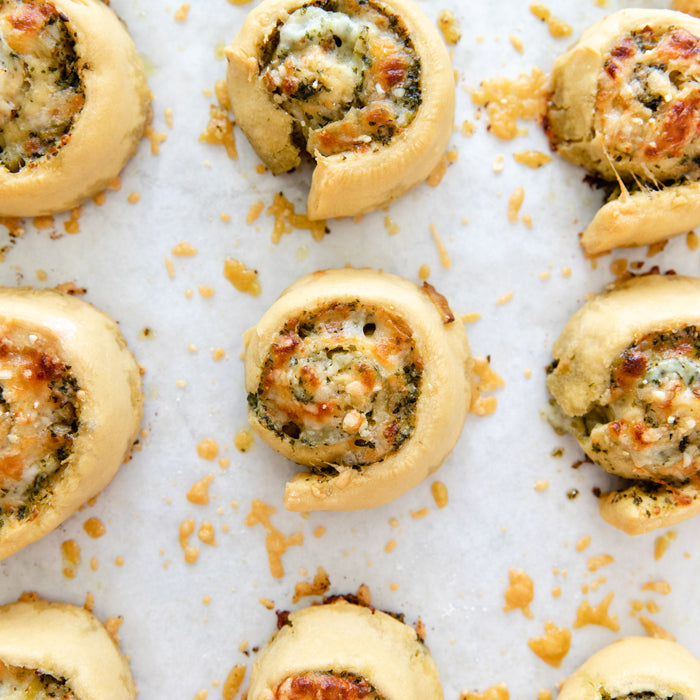 Overhead view of baked einkorn pizza roll-ups filled with cheesy leek and pesto on parchment paper