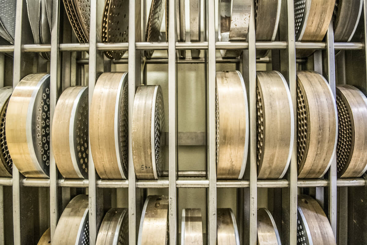 Front view of brass pasta extruder dies stacked on a metal rack in an artisan pasta factory