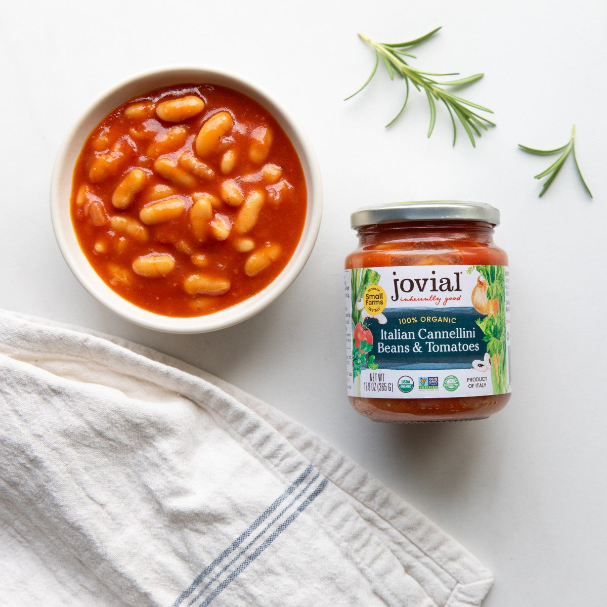 Top-down view of Jovial organic Italian cannellini beans and tomatoes jar with a bowl of beans in tomato sauce