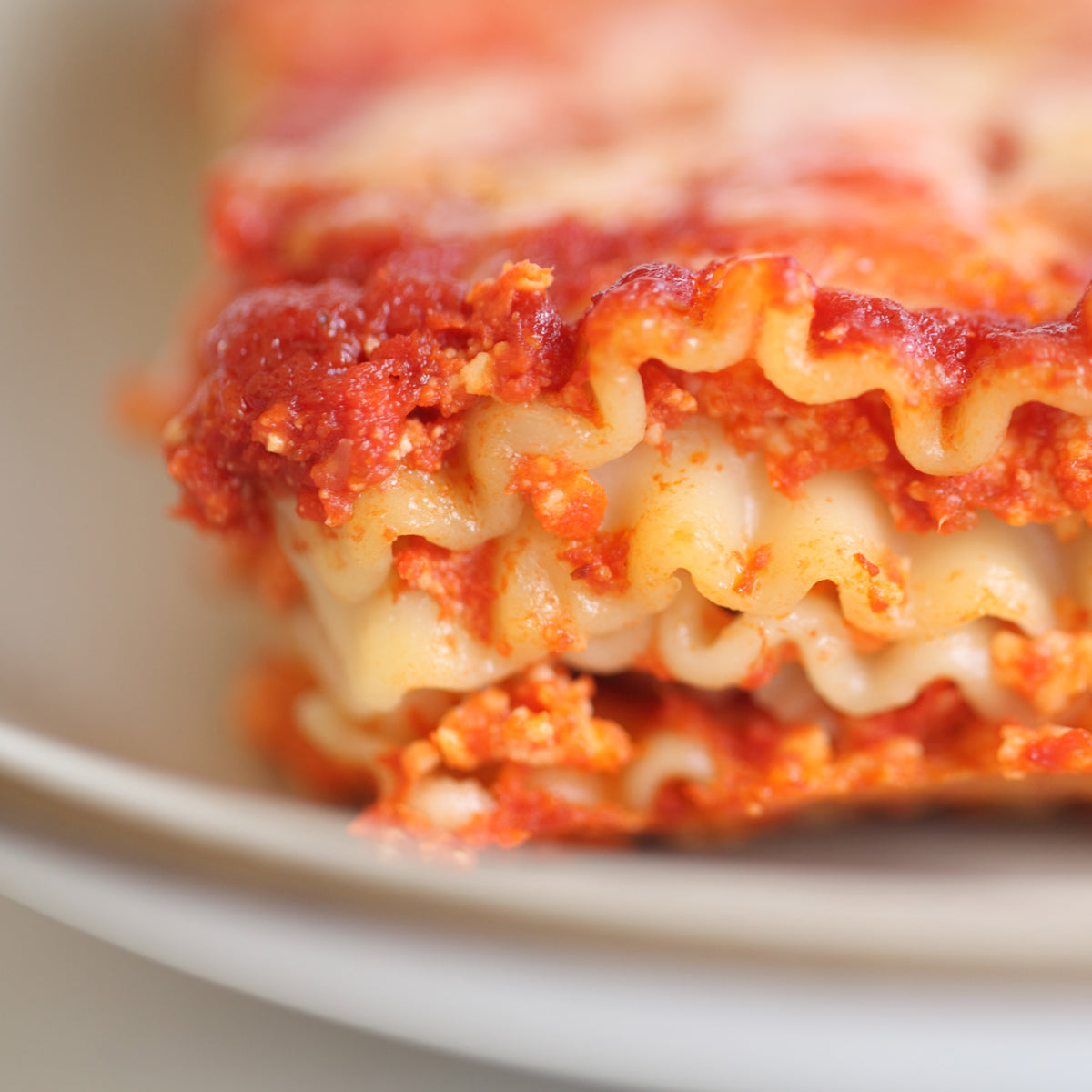 Lasagna slice layered with tomato sauce served on a white plate