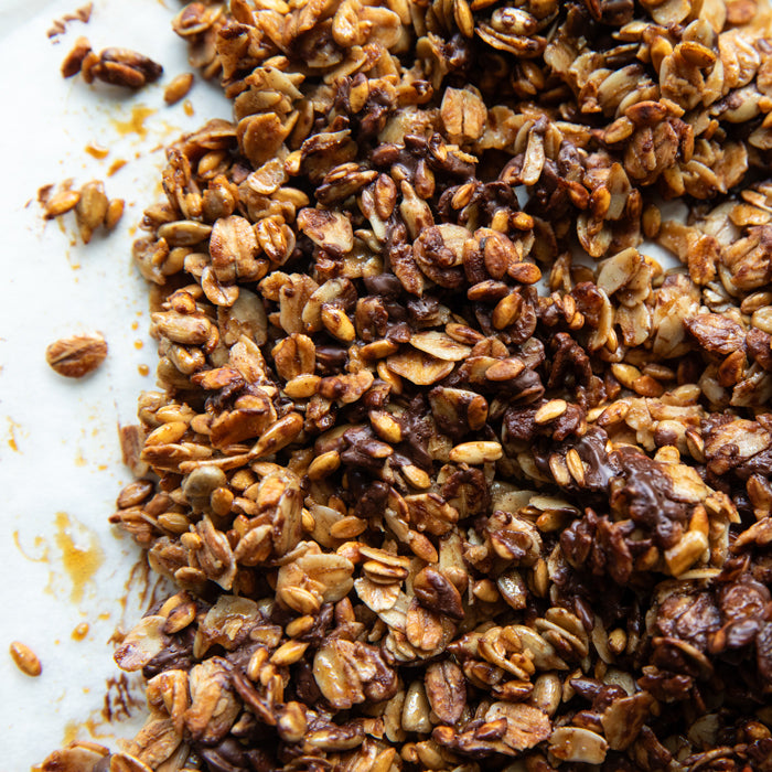 Close-up of chocolate Einkorn wheat berry granola with toasted wheat berries, oats, and chocolate clusters on parchment
