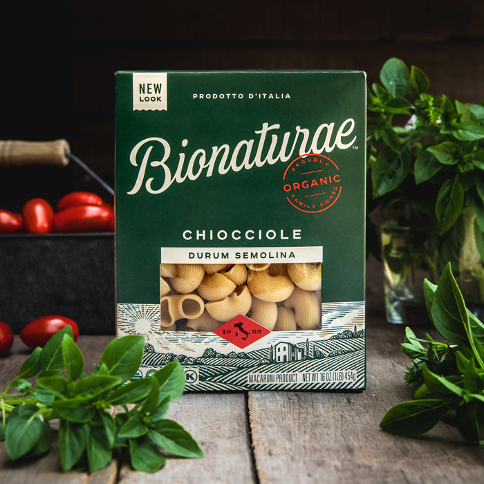 Front view of Bionaturae Chiocciole durum semolina pasta box showing pasta through window with basil and cherry tomatoes