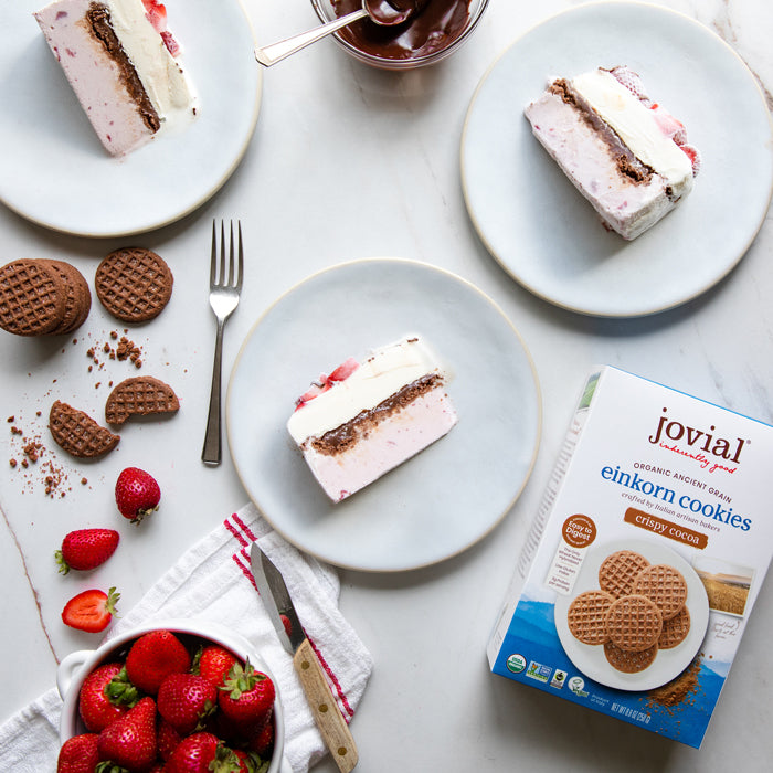 Strawberry vanilla ice cream cake slices with Jovial Einkorn Crispy Cocoa Cookies, fresh strawberries, and a Jovial cookie box