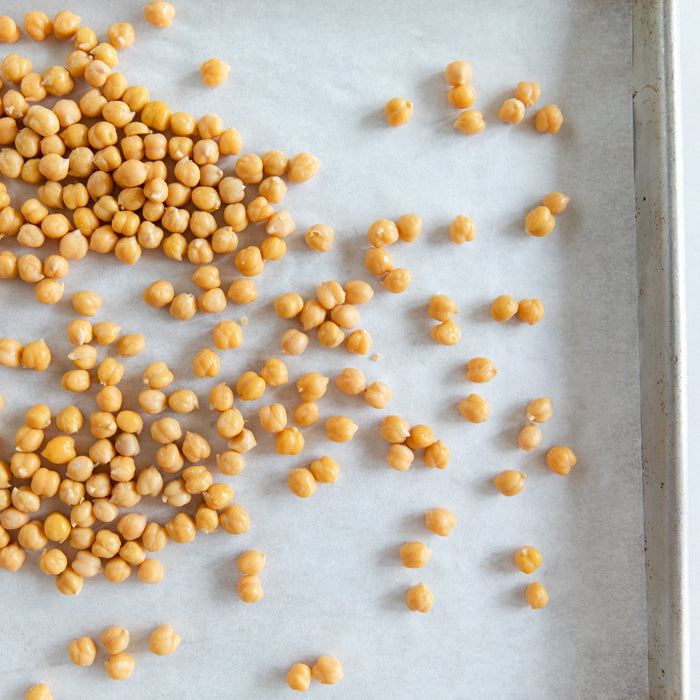 Roasted chickpeas scattered on a parchment-lined baking sheet