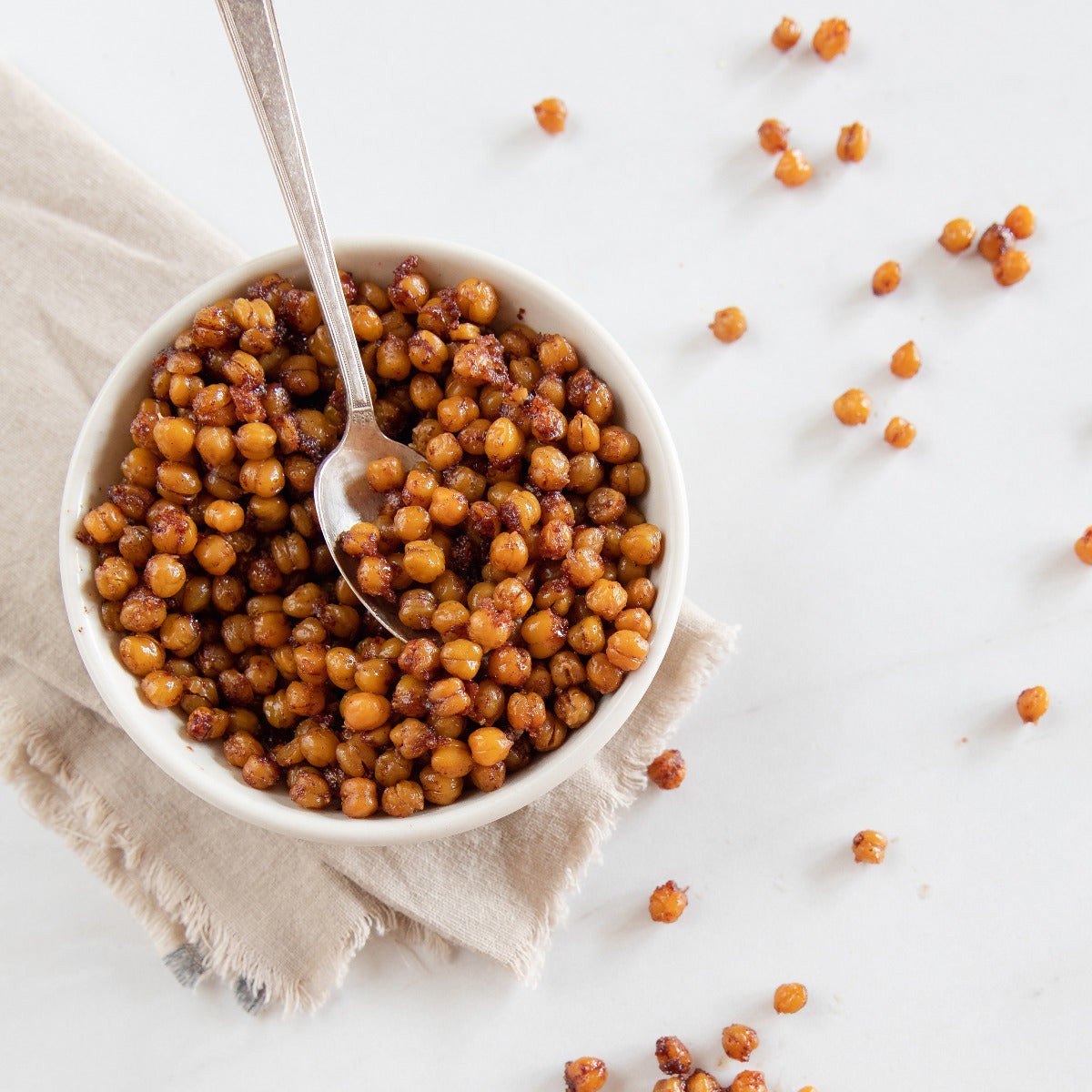 Top-down view of Organic Chickpeas showcasing crispy cinnamon-roasted texture in a white bowl on a white background