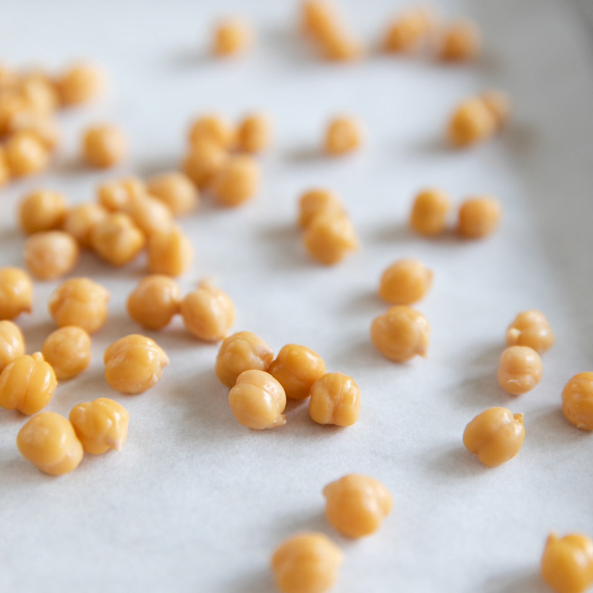 Close-up top-down of Organic Chickpeas showcasing firm cooked beans scattered on parchment-lined surface