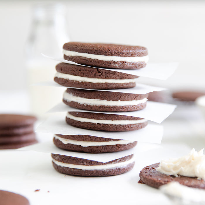 Close-up side view of stacked Einkorn chocolate sandwich cookies showcasing white cream filling with soft white background
