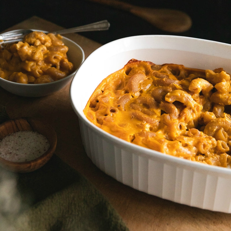 Baked mac and cheese made with organic grain-free cassava elbow pasta in a white casserole dish