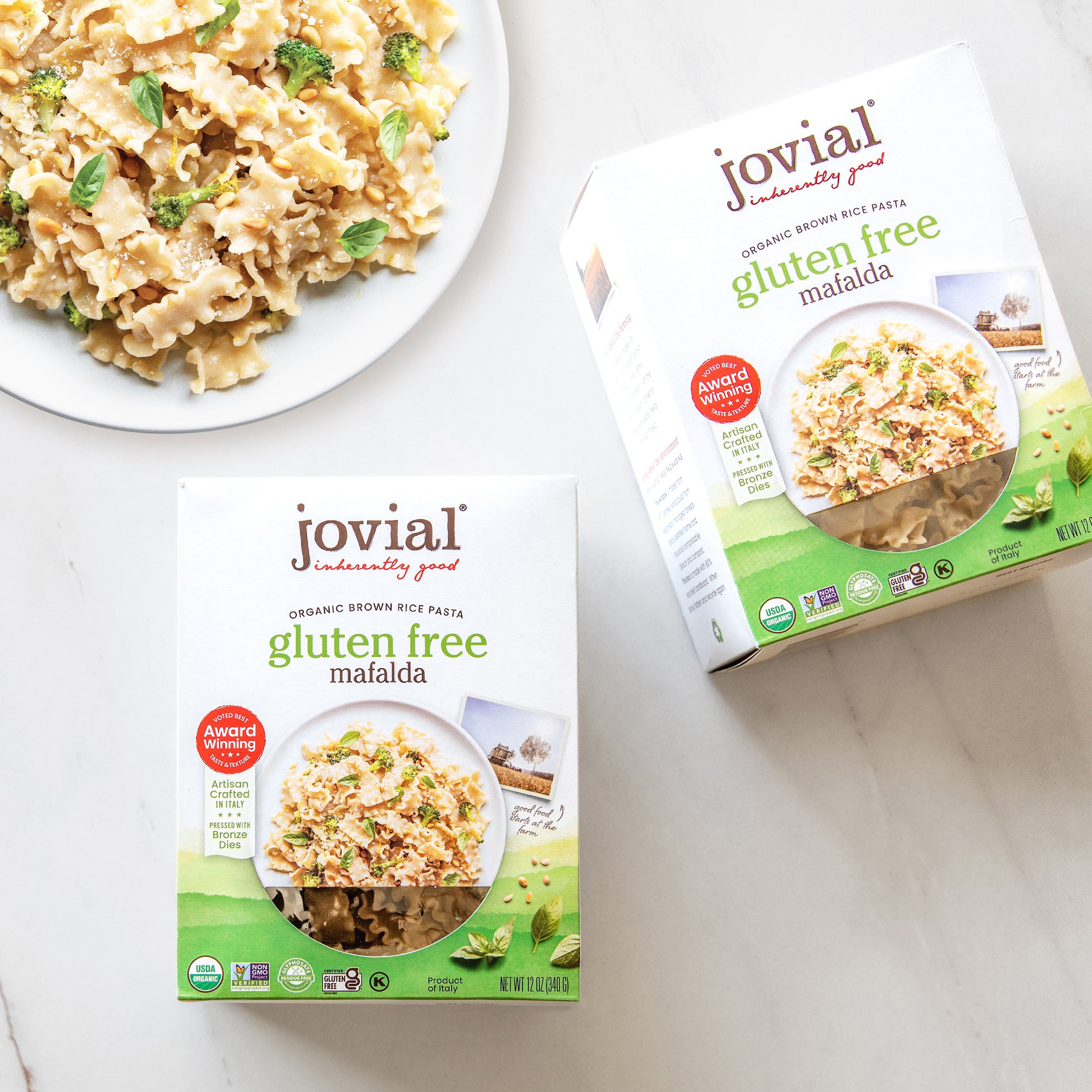 Angled front view of Organic Gluten Free Brown Rice Mafalda boxes showcasing front packaging with serving photo on a light tabletop